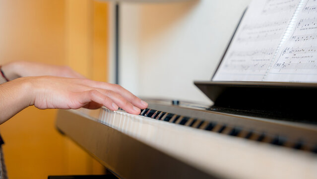 Young woman playing piano with sheet music