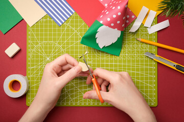 Making a craft. Hands cut out an oval nose from beige paper. Creative process.