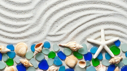 Sea glass and shells arranged on sand with waves pattern  
