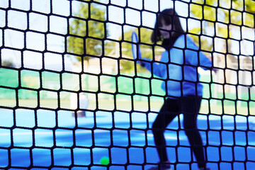 Tennis lessons, children's multi-sport camp. Tennis court with a girl learning to play, out of focus on the other side of the net