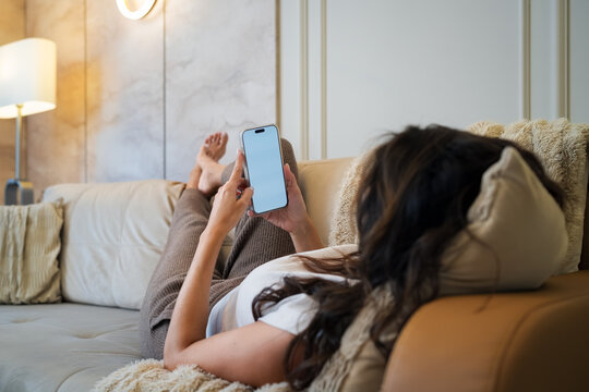 Woman relaxing on sofa with a smartphone