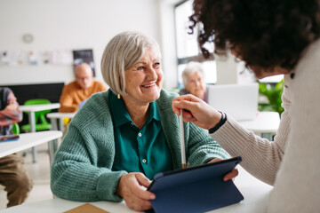 Elderly woman learning digital skills with tutor help.