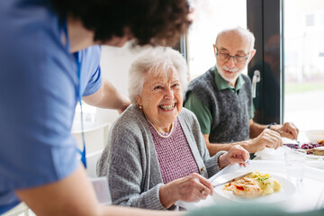 Group of seniors having lunch in community center cafeteria.