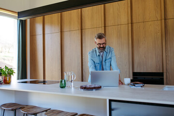 Man working from home office, drinking coffe and working on laptop.