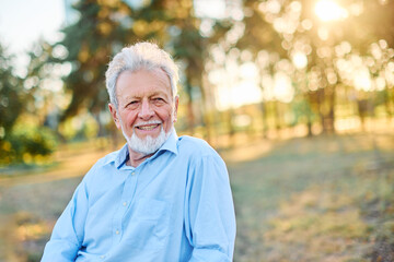 Portrait of an elderly man outdoors. Happy senior man sitting on a bench  in park