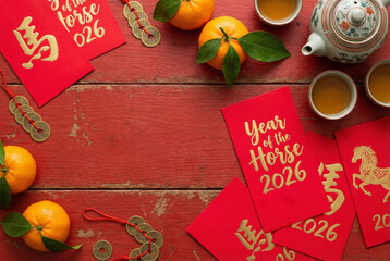 Festive top-down view of red envelopes, mandarins, and tea on wood with large copy space for text