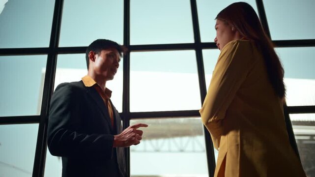 Asian businessman and businesswoman having a serious disagreement in a modern office. Professional partners discussing a conflict