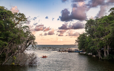 Sunset where river meet the sea, people having fun, kayakers and boats on the shore