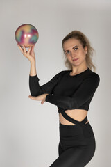 A woman in a tracksuit is practicing finesse. A woman is doing rhythmic gymnastics.