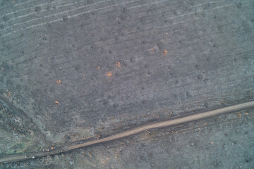 Destroyed military equipment convoy on dirt road among shell craters in war zone aerial drone shot for conflict aftermath and apocalypse