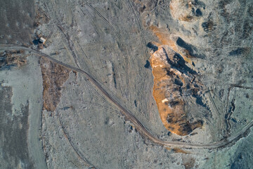 Industrial clay quarry excavation site with winding dirt road and heavy tire tracks aerial drone shot for mining industry and construction