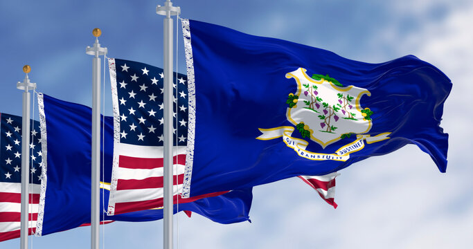 Connecticut state flags waving with national american flags on a clear day.