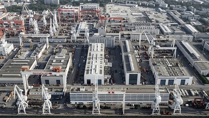 Obraz premium Aerial view of a sprawling industrial port with large white cranes warehouses and shipping containers