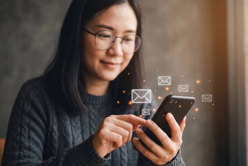 Asian woman in glasses interacting with digital email icons on a smartphone screen