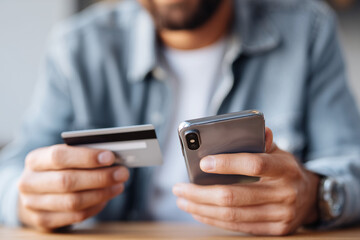 A man is holding a credit card and a cell phone