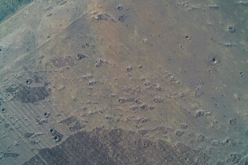 Abstract earth ground texture with natural soil crater patterns and rough dry field surface featuring erosion details, aerial top down view