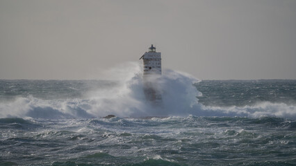 Powerful ocean waves crashing against a lighthouse during intense sea storm