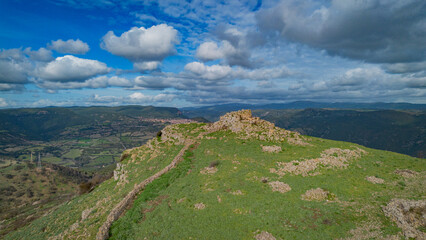 Prehistoric nuraghe stone structure rising from green landscape under dramatic sky in Sardinia