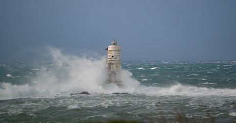 Powerful ocean waves crashing against a lighthouse during intense sea storm