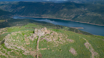 Prehistoric nuraghe stone structure rising from green landscape under dramatic sky in Sardinia