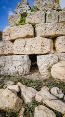 Prehistoric nuraghe stone structure rising from green landscape under dramatic sky in Sardinia