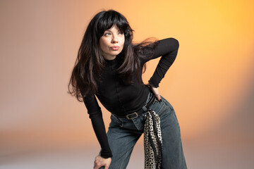 A young brunette poses for a photographer and looks into the camera. A woman poses in a photo studio.