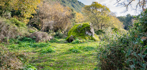 Prehistoric nuraghe stone structure rising from green landscape under dramatic sky in Sardinia