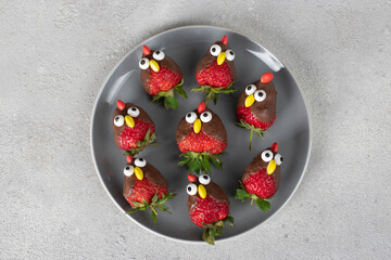Strawberries in chocolate in shape of birds on gray plate, Culinary idea for kids party