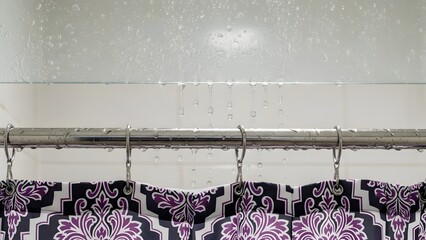 Close up of wet black purple and white floral paisley shower curtain on chrome rod with water droplets