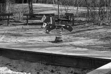 Childhood memories: A nostalgic rocking animal in the shape of a horse on a sandy playground.