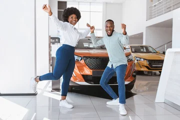 Fotobehang Diamanten Young black couple cheering and dancing, gesturing YES, celebrating purchase of new car at auto dealership. Full length of Afro family buying automobile, feeling excited at showroom store  © Prostock-studio
