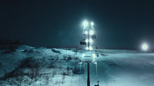 Cableway at the mountain ski resort. Cable car in Arctic, tourists skiing in fog. Falling snow covered trees, powder night. Cold weather. Movement on funicular