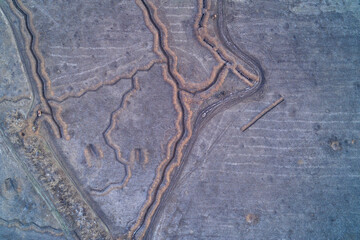 Military defensive trench fortifications with tactical zigzag pattern dug in earth field featuring infantry shelter aerial top down view