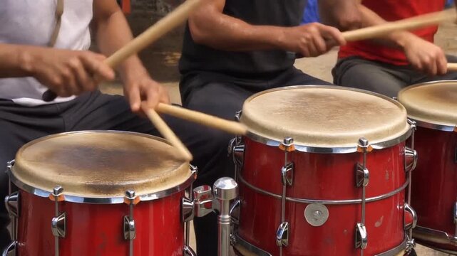 Group of People Playing Red Drums Together.