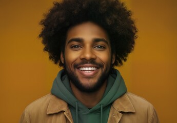 confident african american man with afro smiling against a mustard yellow background