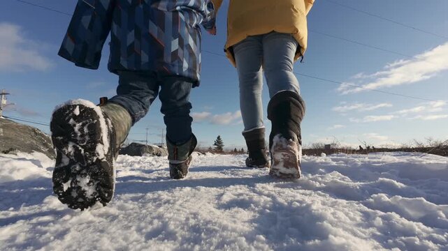 Mother and child walk together on a snowy path in a winter park, seen from behind. Nova Scotia, Canada, winter landscape, family bonding, peaceful outdoor scene and cold season atmosphere.