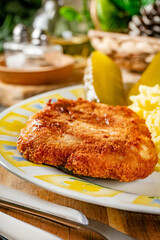 Minced meat cutlet served with mashed potatoes and pickled cucumber.