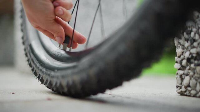 woman hand removes thorn from tire, closeup urban scene with female commuter extracting thorn from bicycle tire on concrete sidewalk, fingers near valve, textured rubber and gravel, quiet morning