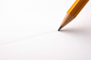 The tip of the pencil draws a thin line on white paper. Space for text.
