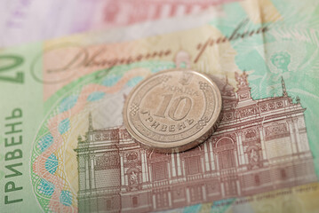 Ukrainian 10 hryvnia coin on banknote background. Close-up of national currency, finance, and economy concept. Selective focus on cash. Savings, budgeting, spending, inflation