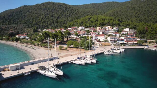 4K Drone footage of Neo Klima village, marina and harbor in Skopelos. Sailing yachts and boats anchored in protected bay. Sporades, Greece.