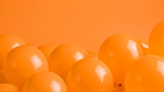A close-up view of many orange balloons with a seamless orange background