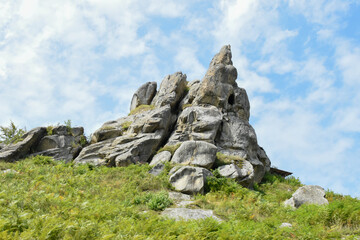 The rock complex of Tustan, ancient city-fortress. Green grass on the hill, sunny day, blue sky. Summer in Carpathians. Lviv oblast, Ukraine.
