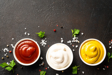 Sauce bowls - mayonnaise, mustard, ketchup on black background.