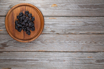 Dried Plums on Worn Wooden Board Background Top View
