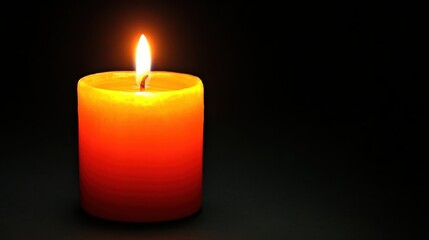 A single candle burning with a bright flame in the darkness providing warmth and illumination