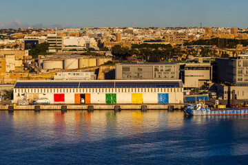 Colorful Waterfront Warehouse Doors Along Harbor With City Skyline At Sunset