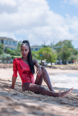 Portrait of Beautiful Caribbean Adult Teen in Barbados. Wearing Red Bikini and Sitting on a tropical beach. 
