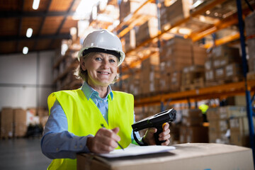 Senior warehouse woman worker working with barcode scanner.