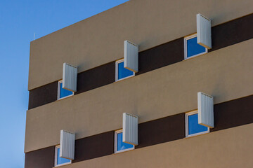 Modern Apartment Building Facade With Shutters, Windows, And Bright Blue Sky